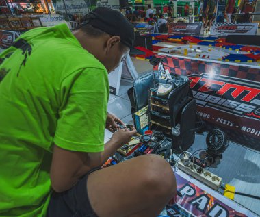 Balikpapan, Indonesia - August 10th, 2024. He is focusing on his Mini 4WD car in preparation for a competition. clipart