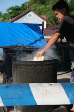 Balikpapan, Endonezya - 12 Eylül 2024. Bozuk para hamuru ince dilimlere ayrılmadan önce varilde kaynatılır..