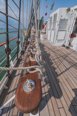 Balikpapan, Endonezya - 24 Ekim 2024. Geminin ahşap güvertesinin yakın çekim görüntüsü, etraflarını kalın halatlarla sarmış birkaç demirleme halatı içeriyor..