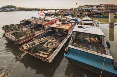 Balikpapan, Indonesia - September 19th, 2024. A fleet of traditional fishing boats rests in a bustling harbor, The Indonesian flag waves proudly atop a nearby building. clipart