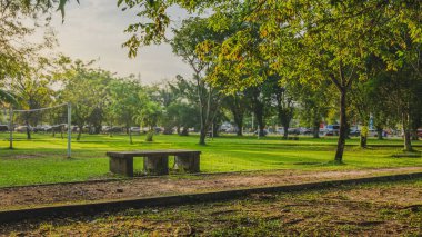 Balikpapan, Endonezya - 3 Eylül 2024. Taştan bir bankı olan yeşil bir park, koşuşturma ve koşuşturmadan huzurlu bir kaçış sağlıyor..