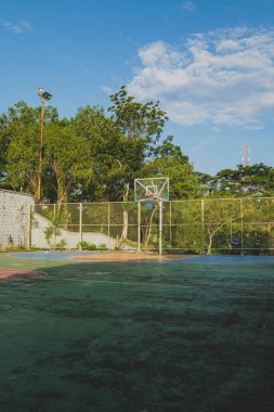 Basketbol potası ve tel örgülü bir basketbol sahası. Görüntü, oyunun ve açık havanın güzelliğini yakalar..