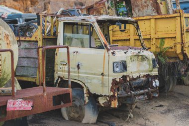 Balikpapan, Endonezya - 19 Kasım 2024. Hurdalıkta terk edilmiş, paslı kamyonlar koleksiyonu..