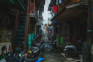 Balikpapan, Endonezya - 15 Aralık 2024. Ara sokak tıka basa dolu evlerle dolu. Motosikletler ara sokağın kenarına park edilmiş..