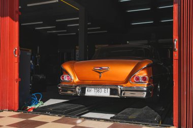 Balikpapan, Endonezya - 18 Aralık 2024. Klasik turuncu 1958 Chevrolet Impala arabası. Parlak krom tamponlu ve stop lambalı. Garaja park edilmiş.