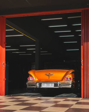 Balikpapan, Endonezya - 18 Aralık 2024. 1958 model Chevrolet Impala arabasının arka tarafındaki yakın çekim. Krom detaylarını açık kapılı bir garajda sergiliyor..