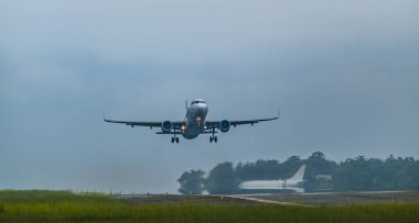 Pistten kalkacak bir ticari uçak. Uçak yukarı doğru açılı, iniş takımları hala görünür durumda..