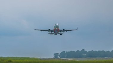 Balikpapan, Endonezya - 13 Ocak 2025. Yağmurlu koşullarda havalanan Airasia ticari jetinin dramatik görüntüsü. Uçak pistten kalkıyor, gökyüzü bulutlu ve atmosfer karamsar.