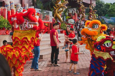 Balikpapan, Endonezya - 29 Ocak 2025. Baba, oğlunun turuncu bir aslan dansına kırmızı bir zarf sunuşunu izliyor..