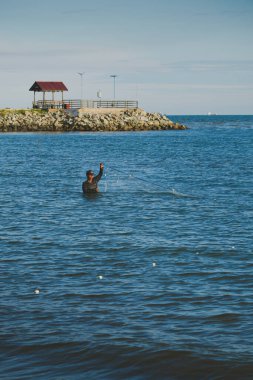 Balikpapan, Endonezya - 3 Mart 2025. Balıkçı öğleden sonra balık tuttuktan sonra kürek çekiyor..