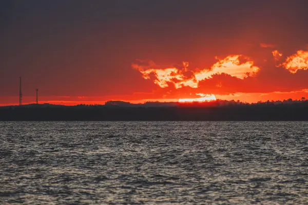 Balikpapan Körfezi 'nde çarpıcı bir günbatımı. Koyu kırmızı bir gökyüzü. Karanlık ufukta parlayan bulutlar..