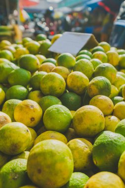 Balikpapan, Endonezya 19 Nisan 2025. Geleneksel bir sokak pazarında sergilenen olgun yeşil ve sarı limonları kapat.