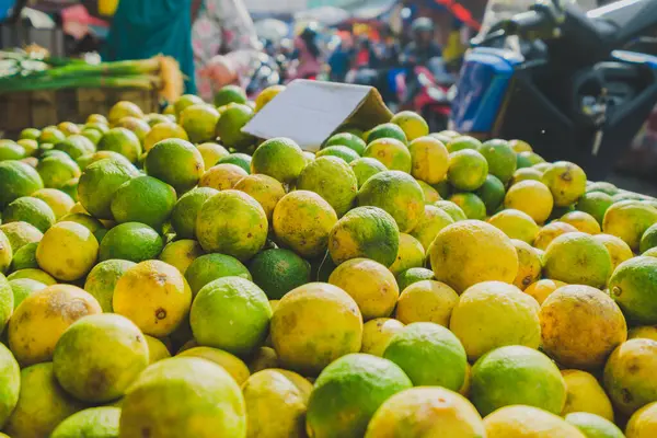 Balikpapan, Endonezya 19 Nisan 2025. Geleneksel bir sokak pazarında sergilenen olgun yeşil ve sarı limonları kapat.