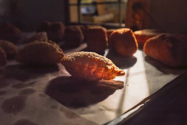 Bir yığın altın, çıtır çıtır pastalar taze kızartılmış, bir tanesi de belirgin bir şekilde mutfak ışığı ile işaretlenmiş. Ev yapımı aperatif hazırlama sahnesi.