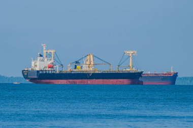 Balikpapan, Endonezya - 4 Mayıs 2025. Açık bir gökyüzünün altında, sakin, mavi bir denizde iki büyük yük gemisi..