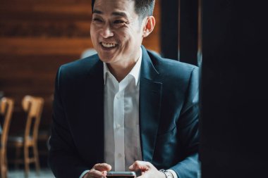 Kahve dükkanında cep telefonu kullanan mutlu iş adamı.