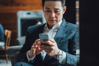 Kahve dükkanında cep telefonu kullanan ciddi bir işadamı.