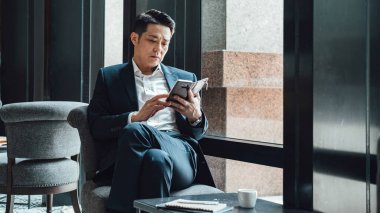 Kahve dükkanında cep telefonu kullanan ciddi bir işadamı.