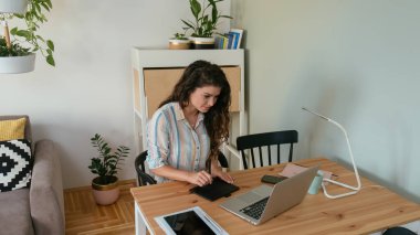 Evde dizüstü bilgisayarla çalışan mutlu iş kadınının fotoğrafından ve pedlerden.