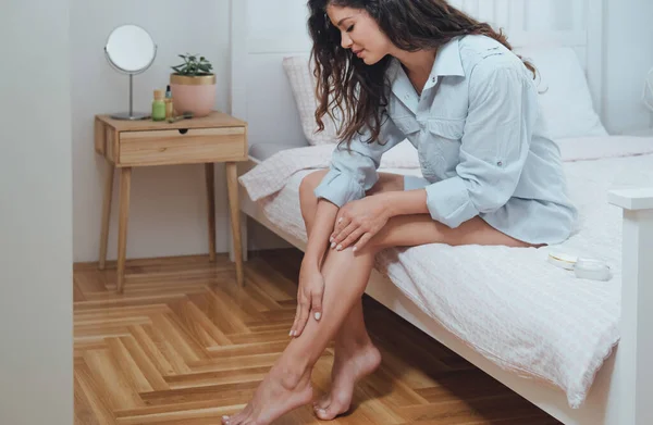 Gülümseyen Kadın Yatak Odasında Bacaklarına Vücut Losyonu Sürüyor — Stok fotoğraf