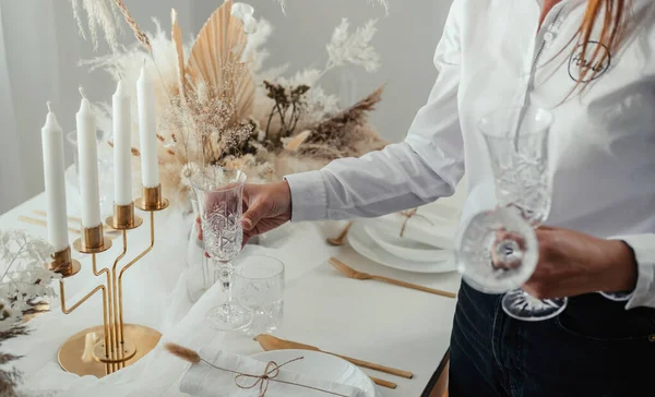 High angle view of an anonymous woman putting crystal glasses on a table and preparing Christmas dinner party at home