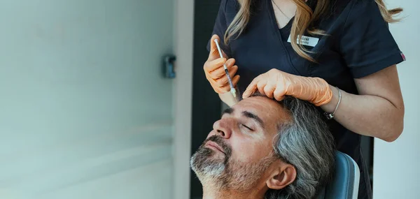 額に男性患者のボトックス注射を与える匿名の女性美容師 ストック写真