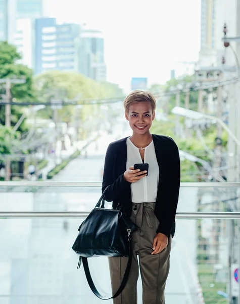 Portrait Of Happy Business Woman Using A Mobile Phone At Office Balcony With City View