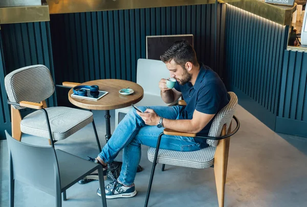 カフェに座ってエスプレッソを飲みながら携帯電話を使うシリアスビジネスマンの上から ストック画像