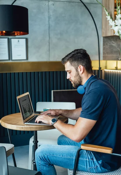 コーヒーショップに座っている間 ノートパソコンのキーボードにビジネスレポートを入力している深刻な男コーヒーカップ ロイヤリティフリーのストック画像