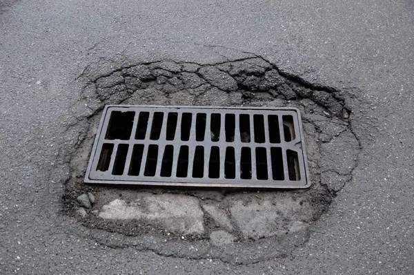 Kırık asfaltın ortasında kırık bir ızgara ızgarası..