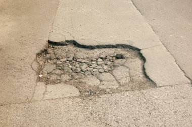 Eski, hasarlı bir yolda asfaltta bir çukur, aşınma ve çürümeyi gösteriyor..