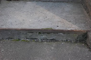 Metal kenarlı eski kırık bir adım, yosun dolu çatlaklar, harap olmuş bir ortamda çürümeyi ve terk edilmeyi gösteriyor..