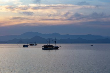 Endonezya 'daki Komodo Ulusal Parkı' nda sakin bir gün doğumu silueti küçük tekneler gösteriyor. Bu güzel park tüple dalış, şnorkelle yüzme ve Komodo ejderhalarını görmekle ünlüdür..