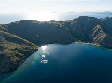 Sabah güneşi Endonezya 'da Komodo yakınlarındaki bir adanın güzel sahil şeridini aydınlatır. Mercan Üçgeni 'nin bir parçası olan bu bölge olağanüstü deniz biyolojik çeşitliliğiyle bilinir..