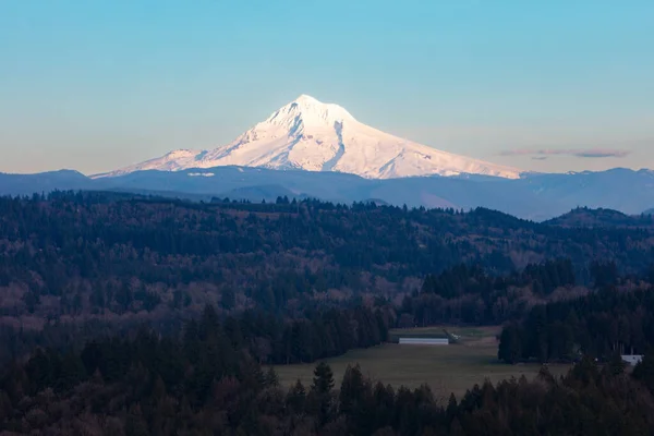 Evening light illuminates Mount Hood  about 50 miles east of Portland, Oregon. This beautiful Pacific Northwest mountain is a potentially active stratovolcano covered by snow much of the year.
