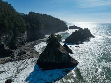 Afternoon sunlight shines on the Samuel H. Boardman State Scenic Corridor along the southern coast of Oregon. This beautiful, rugged coastline is thickly forested and full of amazing viewpoints.