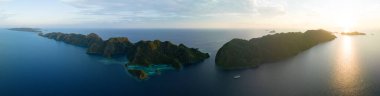 Gün doğumu, Raja Ampat 'ın güzel deniz manzarasından doğan dramatik kireçtaşı adalarını aydınlatır. Endonezya 'nın bu uzak bölgesi inanılmaz deniz biyolojik çeşitliliğiyle bilinir..