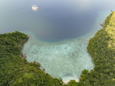 Raja Ampat 'ın güzel kayalık adalarının hemen kıyısında küçük bir fenisi dalış teknesi denize açılıyor. Endonezya 'nın bu uzak bölgesi inanılmaz deniz biyolojik çeşitliliğiyle bilinir..