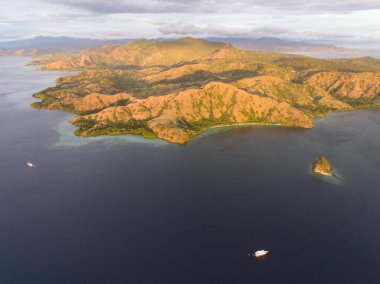 Akşam ışığı Endonezya 'daki Komodo Ulusal Parkı' ndaki Rinca Adası 'nı aydınlatıyor. Rinca, Komodo Adası 'na yakın bir yerde birçok Komodo ejderhasının evidir ve güzel mercan resifleriyle çevrilidir..