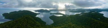 Gün ağarırken, Endonezya 'nın Raja Ampat kentindeki Batanta adasında alçak, güneşli bulutlar sürükleniyor. Bu bölge inanılmaz yüksek deniz biyolojik çeşitliliği nedeniyle Mercan Üçgeni 'nin kalbi olarak bilinir..