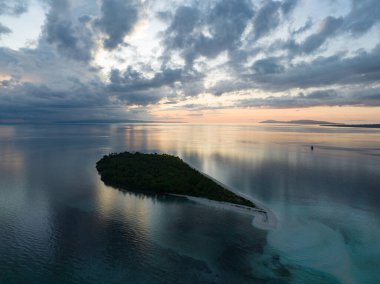 Seram, Endonezya yakınlarındaki uzak Koon adasını huzurlu bir gündoğumu aydınlatır. Bu manzaralı adanın mercan resifleri ve çevreleyen denizler olağanüstü deniz biyolojik çeşitliliğini destekler..