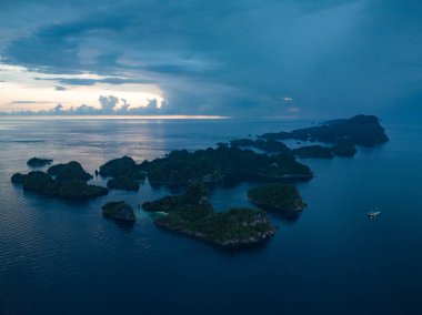 Misool, Raja Ampat, Endonezya 'daki etkileyici deniz manzarasından kireçtaşı adaları yükselir. Bu manzaralı adaların mercan resifleri ve çevreleyen denizler olağanüstü deniz biyolojik çeşitliliğini destekler..