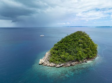 Resiflerle çevrili bir kireçtaşı adası, Raja Ampat 'ın tropikal deniz manzarasından yükseliyor. Endonezya 'nın bu bölgesi, orada bulunan yüksek deniz biyolojik çeşitliliği nedeniyle Mercan Üçgeni' nin kalbi olarak bilinir..