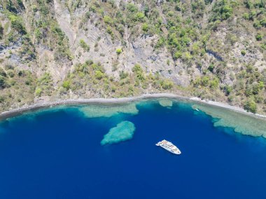 Komba adasının manzaralı ve engebeli kıyı şeridi, Endonezya 'nın Küçük Sunda Adaları' nın 70 km kuzeyinde yer almaktadır. Resiflerle çevrili bu uzak ada, sık sık patlayan aktif bir volkandır..