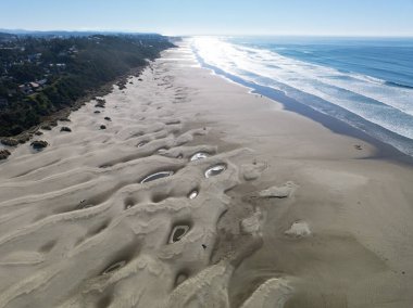 Newport kasabasındaki Oregon Sahil Otobanı boyunca yer alan Agate Sahili 'nde parlak güneş ışığı parlıyor. Bu güzel plaja demir oksit renkli akik bolluğunun adı verilmiştir..