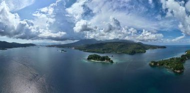 Bulutlar Lembeh Boğazı üzerinde sürükleniyor, Kuzey Sulawesi 'yi Lembeh Adası' ndan ayırıyor. Bu tropikal alan deniz biyolojik çeşitliliğinin bolluğuna ev sahipliği yapar ve dalgıçlar arasında popülerdir..