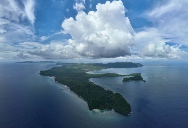 Bulutlar Endonezya, Sulawesi 'nin kuzeyindeki Bangka Adası' nda deniz manzarası boyunca sürükleniyor. Bu tropikal alan, yüksek deniz biyolojik çeşitliliği nedeniyle tüplü dalış ve şnorkelle dalış için popüler bir yerdir..