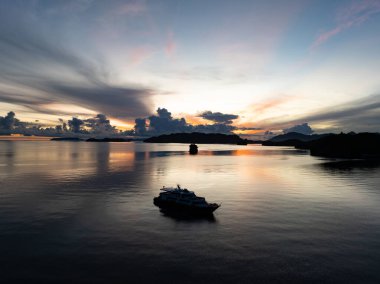 Endonezya 'nın merkezi Sulawesi' nin Togian Adalarını çevreleyen sakin denizlerin ortasında, zarif bir gündoğumu küçük bir tekneyi aydınlatır. Ekvatorun hemen güneyindeki bu güzel alan geniş bir deniz biyolojik çeşitliliğine ev sahipliği yapıyor..