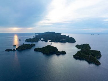 Misool, Raja Ampat 'ın ılık denizlerindeki engebeli kireçtaşı adalarının üzerinde bulutlar asılı. Bu tropikal bölge, olağanüstü deniz biyolojik çeşitliliği nedeniyle dalgıçlar ve şnorkelliler için popüler bir yerdir..