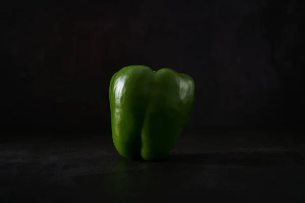 Green bell pepper isolated against a black background. Vegetables artfully presented. Close up of a nutritious paprika. Food artistically presented.
